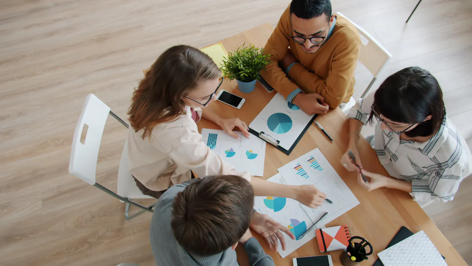 Four colleagues reviewing charts and reports around a table